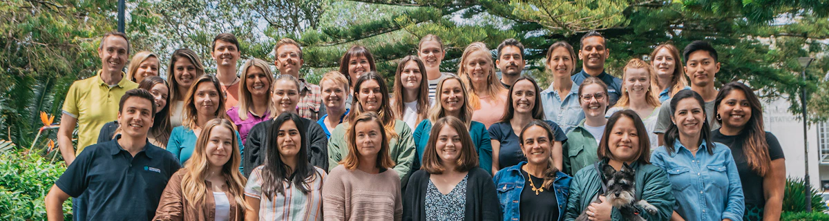 International Volunteer HQ Team of 30 people of various age & ethnicities stand for a group photo in a park in New Plymouth, New Zealand.