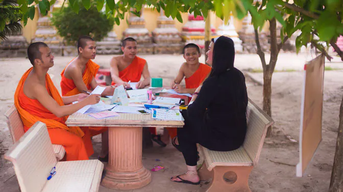 An IVHQ volunteer teaching monks in Laos