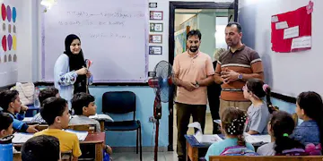Volunteers and local teachers engage a classroom of young students during an English lesson as part of IVHQ’s Teaching English project in Cairo, Egypt, with vocabulary written on the whiteboard behind them.