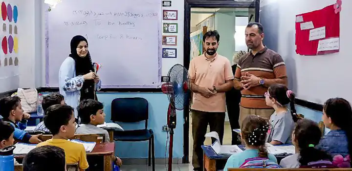 Volunteers and local teachers engage a classroom of young students during an English lesson as part of IVHQ’s Teaching English project in Cairo, Egypt, with vocabulary written on the whiteboard behind them.